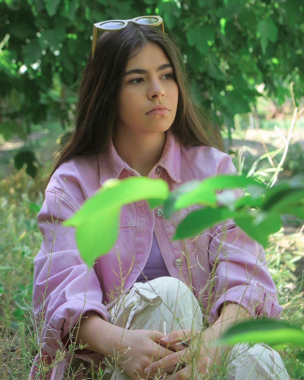 a woman sitting in the grass wearing sunglasses