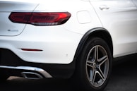 A close-up rear view of a white Mercedes-Benz SUV, focusing on the tail light, rear tire, and part of the bumper. The 4MATIC badge is visible, along with the Michelin branding on the tire.