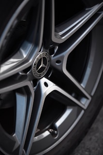 Close-up of a polished car wheel reflecting sunlight on a clean surface.