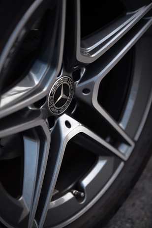 Close-up of a polished car wheel reflecting sunlight on a clean surface.