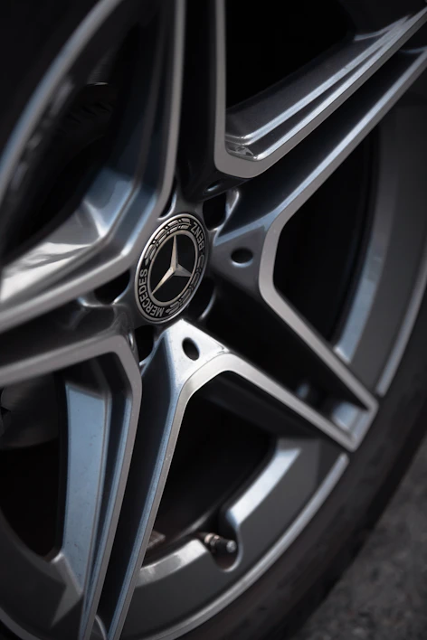 Close-up of a shiny alloy car wheel with intricate spokes reflecting sunlight.