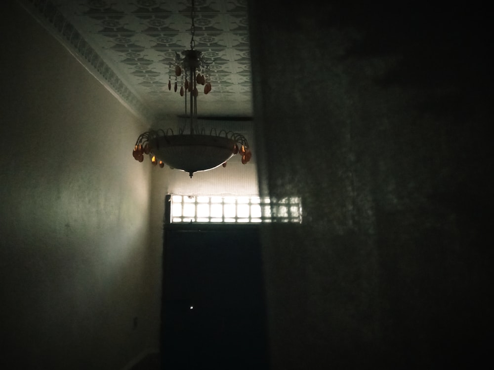 a dark hallway with a chandelier hanging from the ceiling