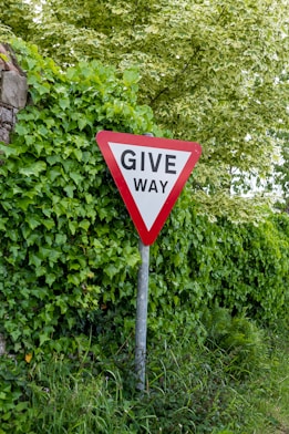 a red and white give way sign sitting on the side of a road