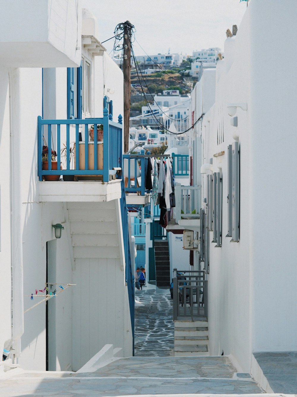 a narrow alley way with blue balconies and white buildings