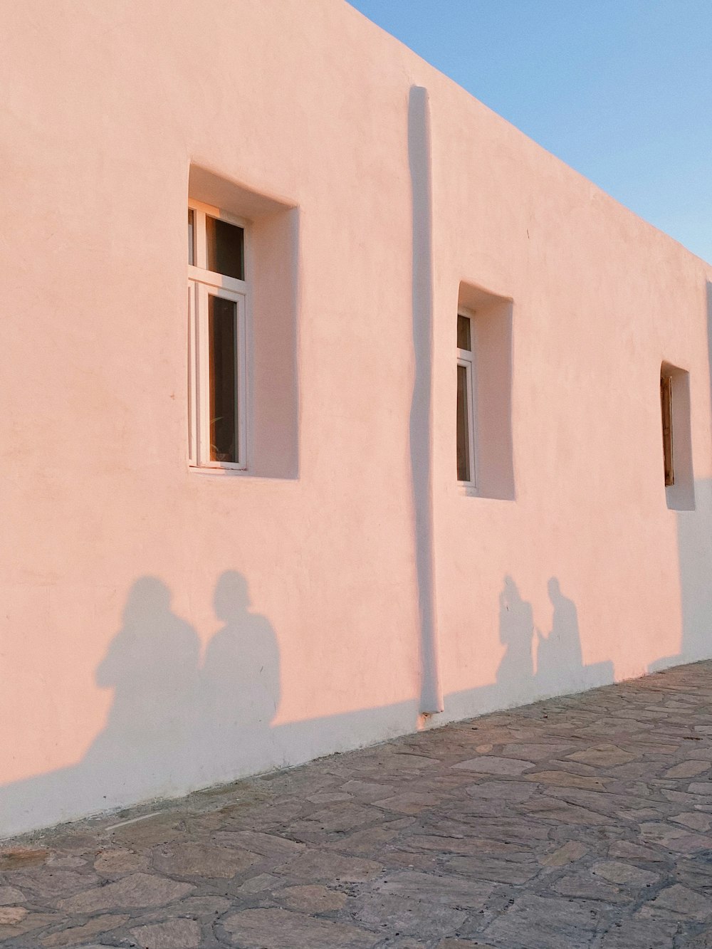 a person standing next to a pink building