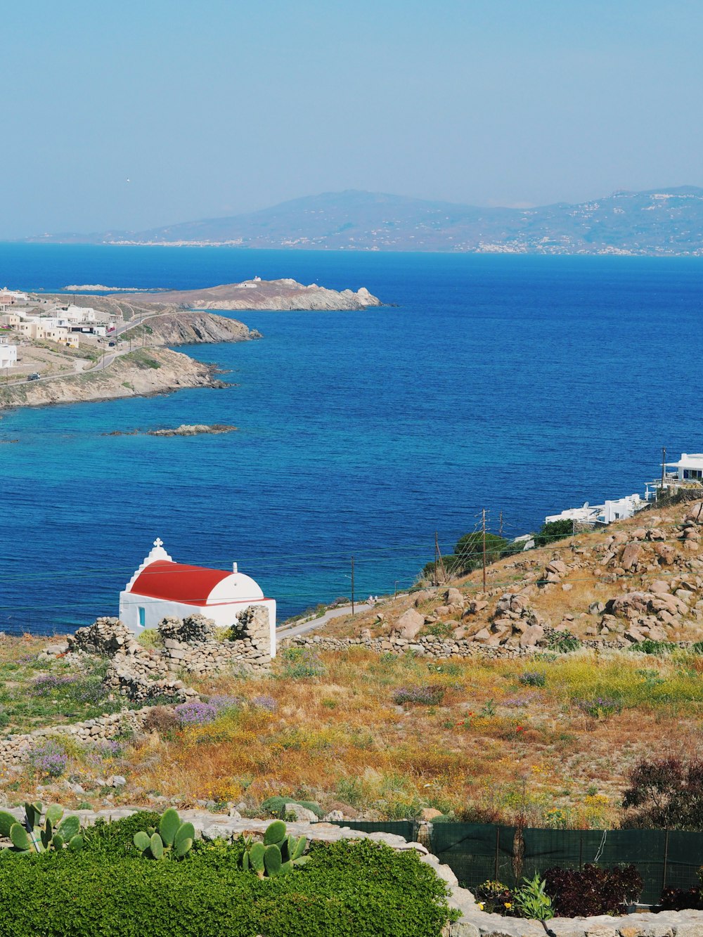 a small white house sitting on top of a hill next to a body of water