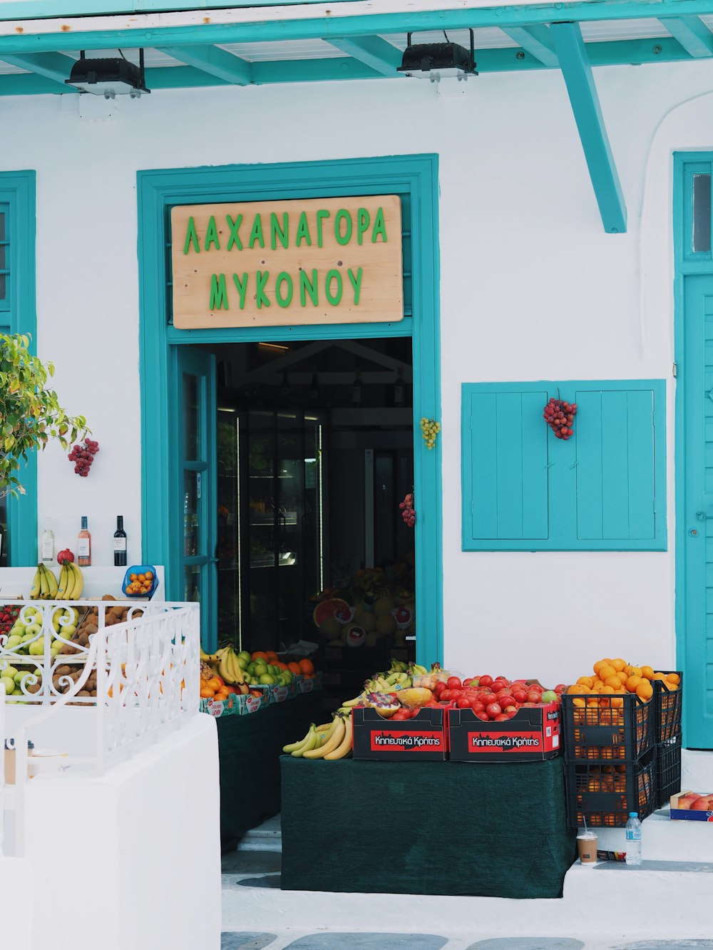 a fruit stand in front of a building with blue shutters