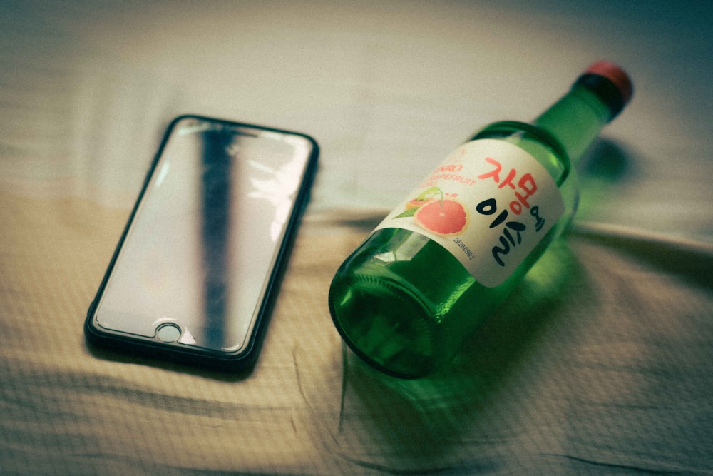 a bottle of beer and a cell phone on a bed