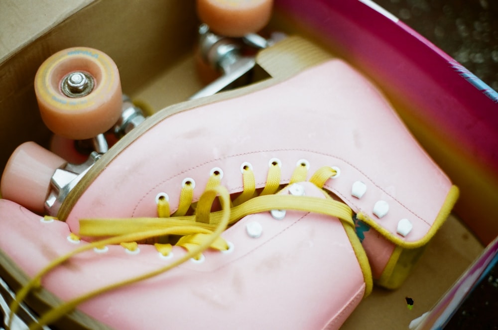 a pink skateboard with yellow laces in a box