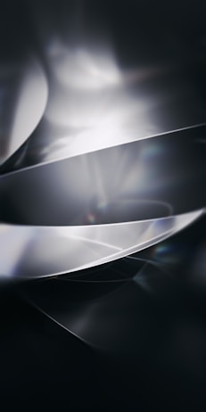 Abstract composition featuring smooth, curved surfaces with a glossy texture, reflecting light and creating a sense of movement. The interplay of light and shadow gives a futuristic and sleek appearance.