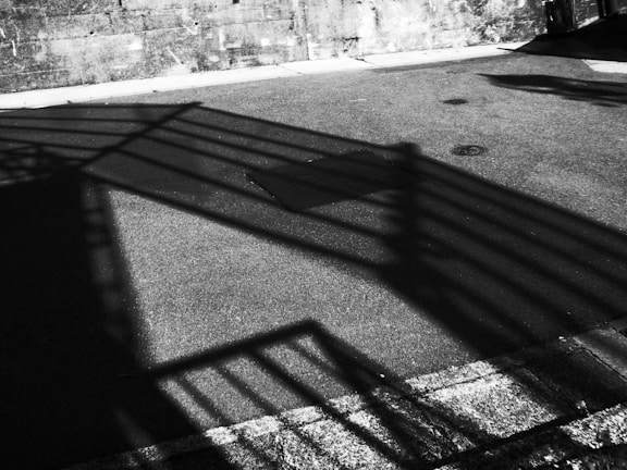 High-contrast image of a streetwear shirt hanging with shadows mimicking cracked concrete patterns.