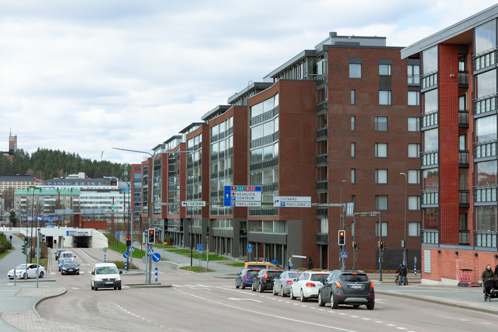 a group of cars driving down a street next to tall buildings