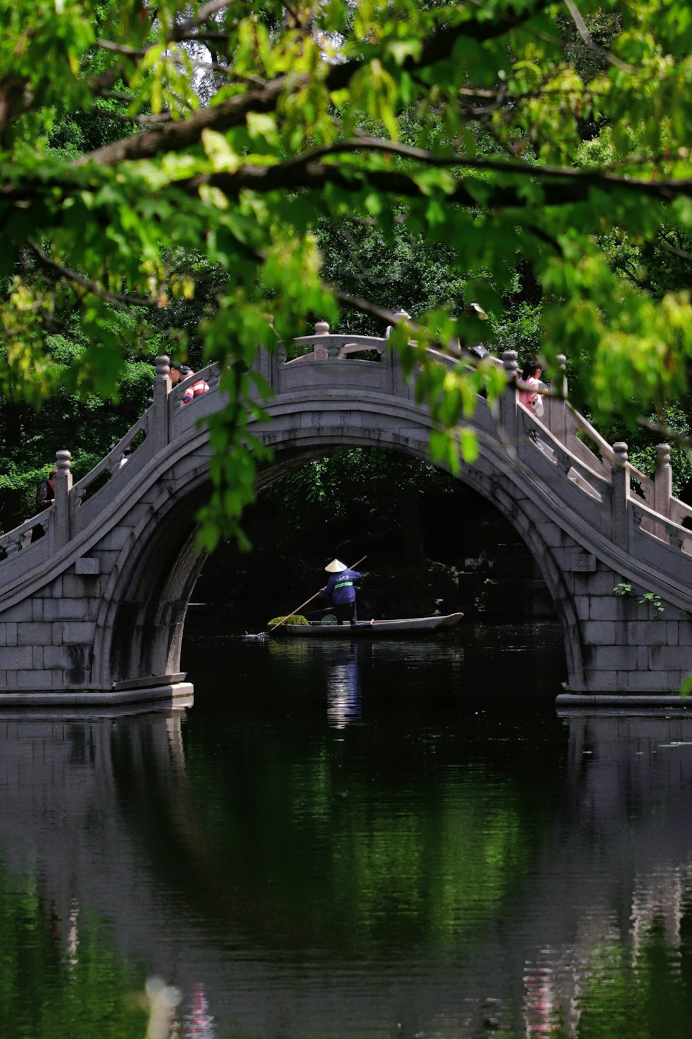 a man rowing a boat under a bridge