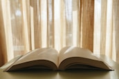 An open book on a table, surrounded by a warm, inviting study environment with soft lighting.