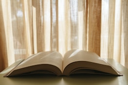 An open book on a table, surrounded by a warm, inviting study environment with soft lighting.