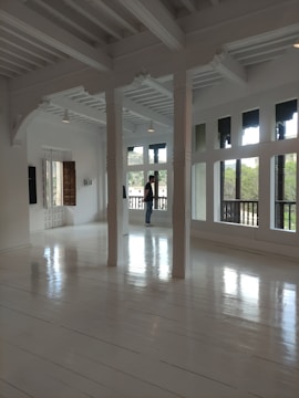A worker cleaning a spacious living room with sunlight streaming in.