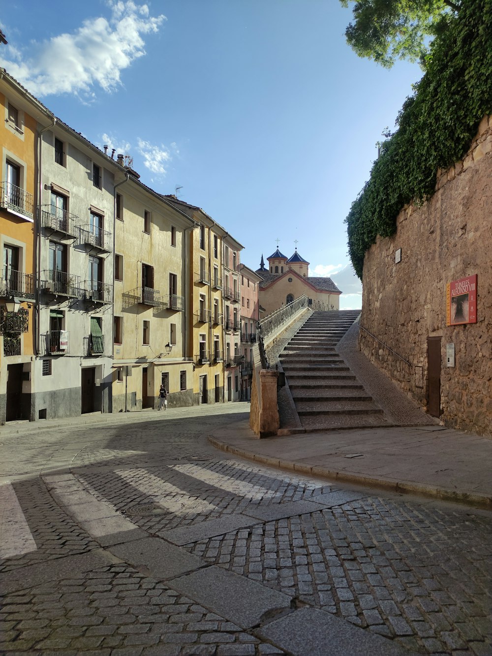 a cobblestone street lined with buildings and stairs