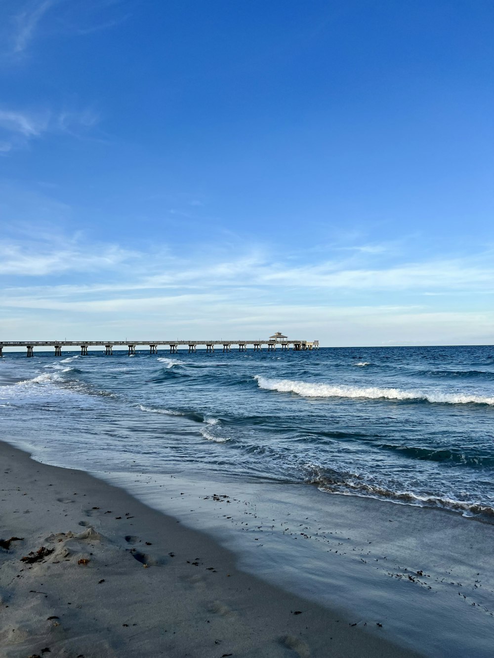 a beach with a pier in the distance