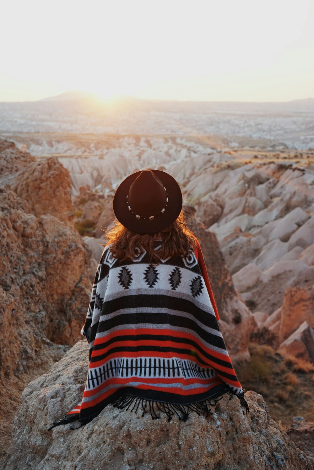Una mujer sentada encima de una roca cubierta con una manta