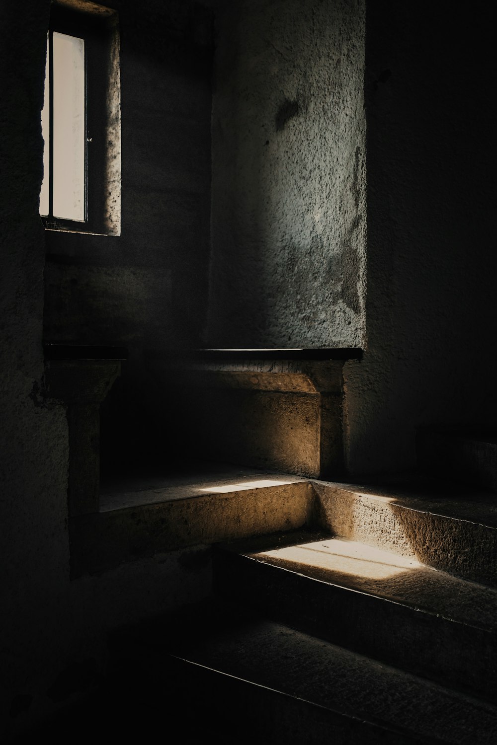 a dark room with some stairs and a window