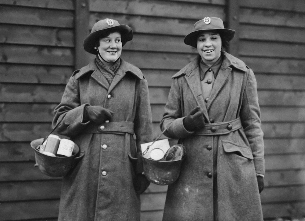 two women in coats and hats are standing together