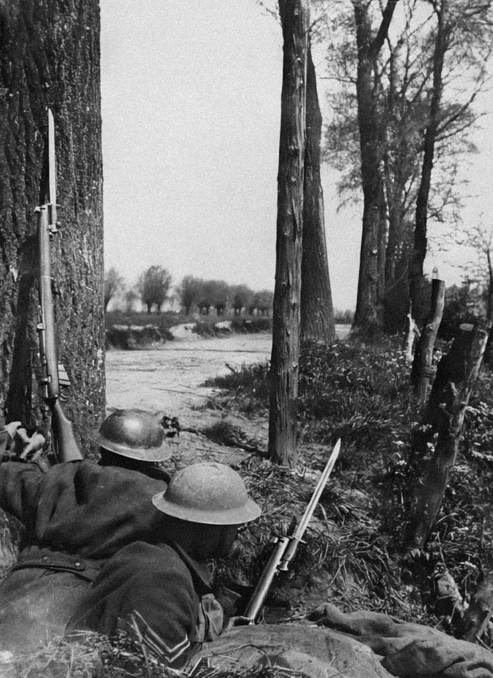 Ein Schwarz-Weiß-Foto eines Mannes, der mit einer Waffe auf dem Boden liegt