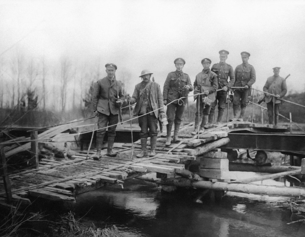 a group of men standing on top of a wooden bridge