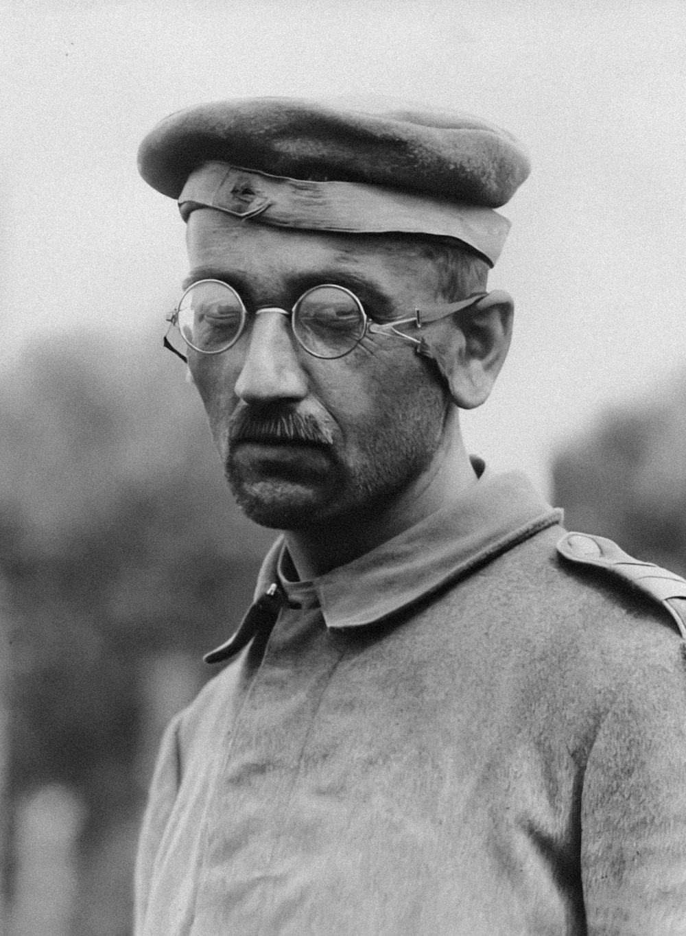 a black and white photo of a man wearing a hat and glasses