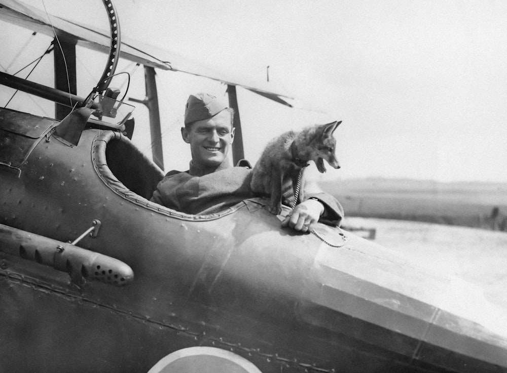 a black and white photo of a man in an airplane with a dog on his