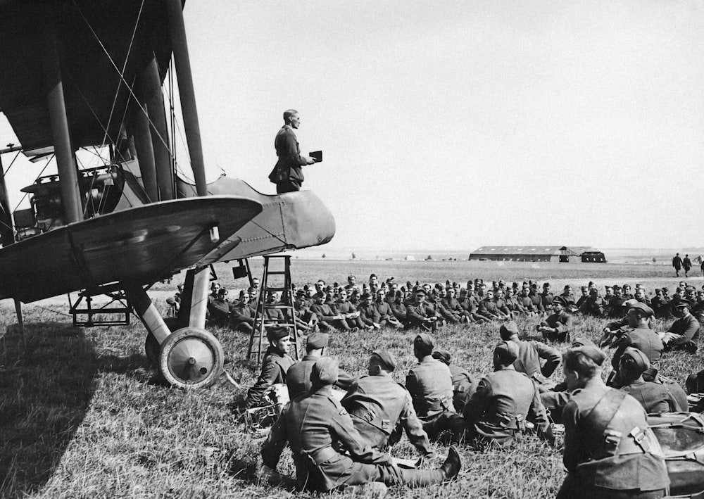 a man standing on top of a plane in a field