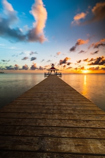 A wooden pier extending into the ocean at sunset