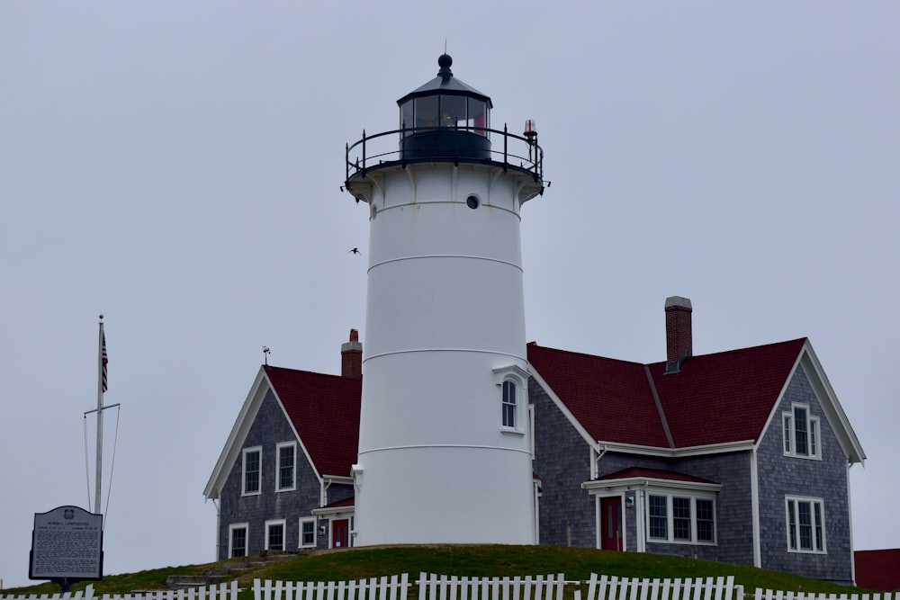 a white house with a red roof and a black and white lighthouse