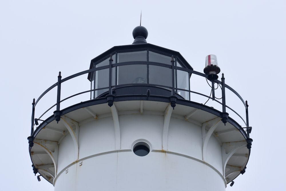 a white and black lighthouse with a sky background