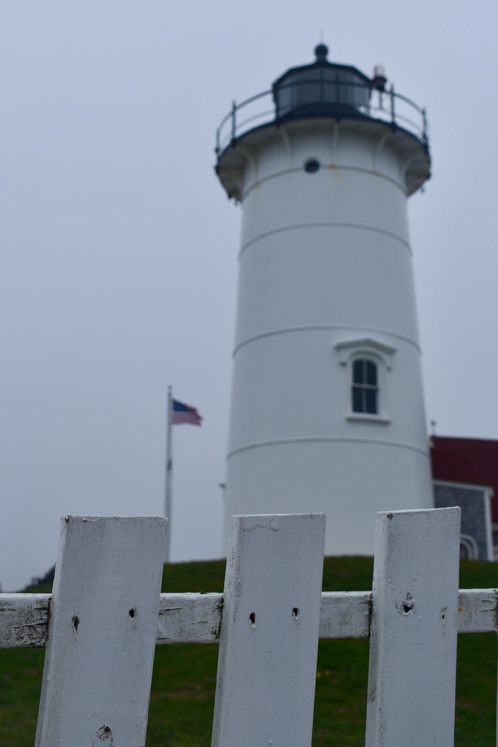 a white fence with a lighthouse in the background