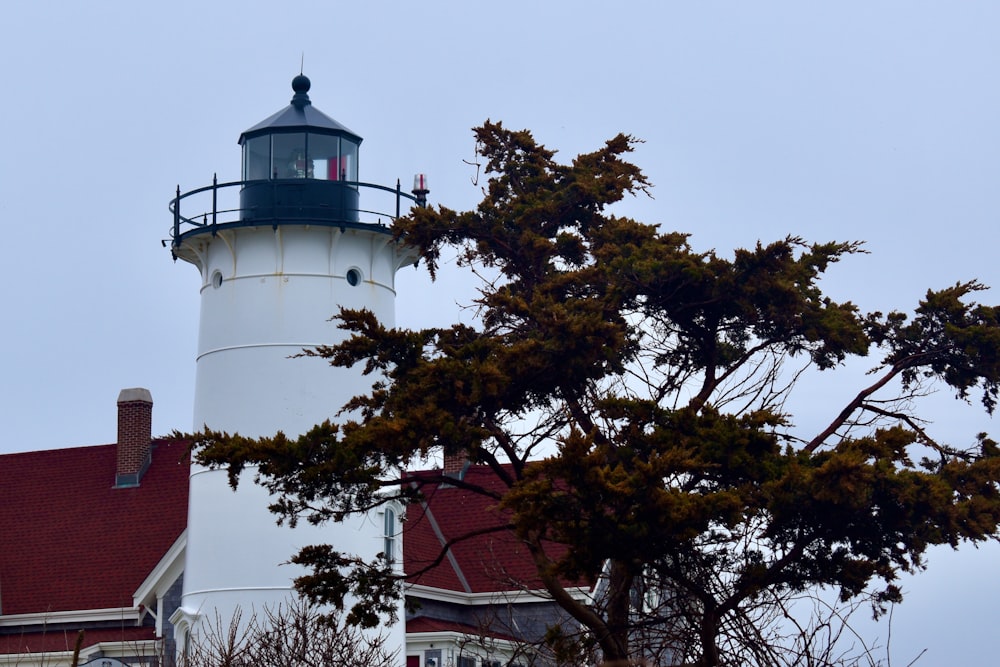 a white and black lighthouse with a red roof