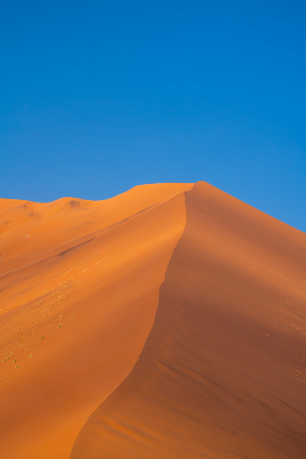 a large sand dune with a blue sky in the background