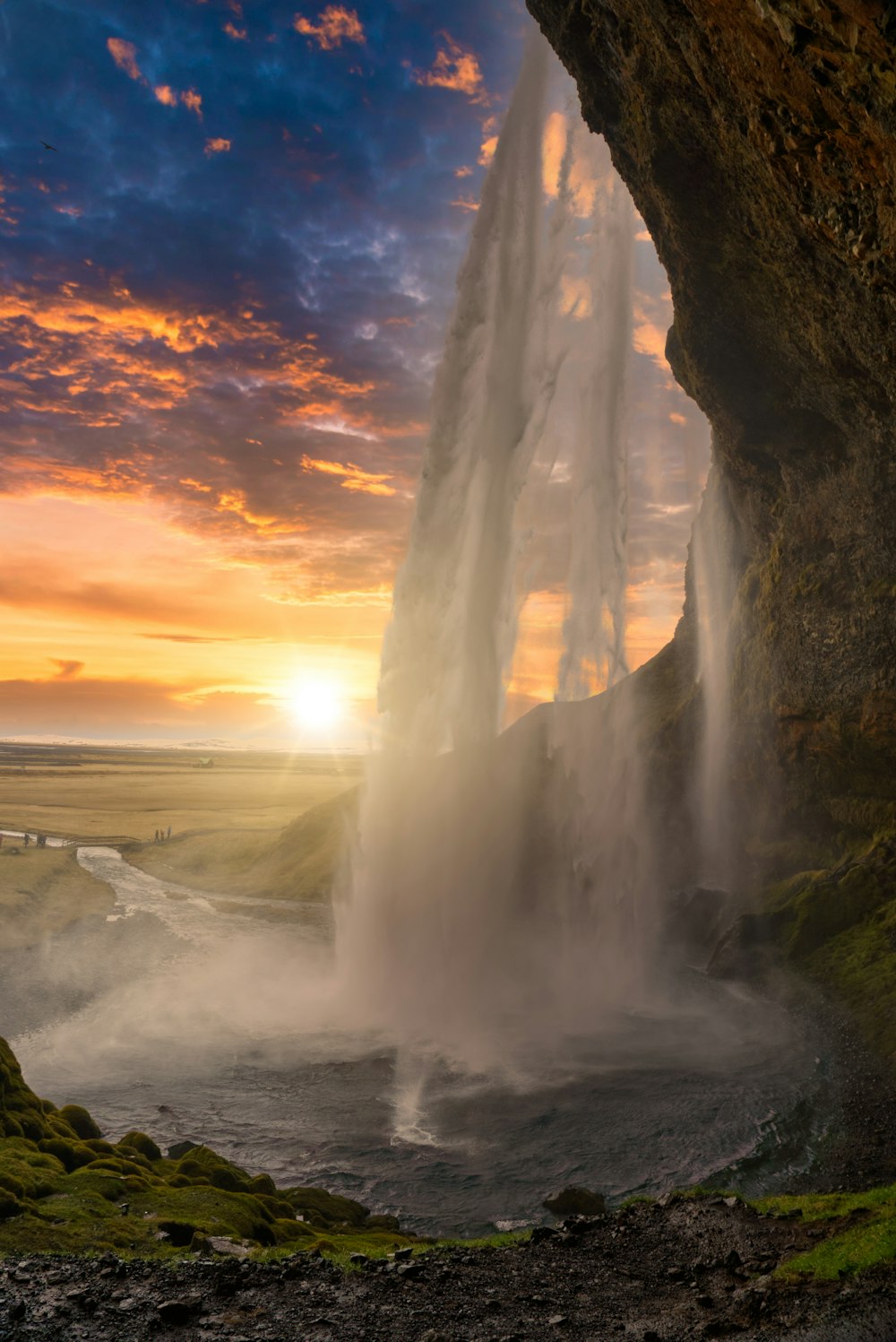 the sun is setting behind a waterfall