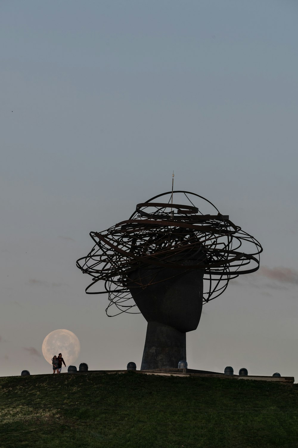 Due persone in piedi sulla cima di una collina sotto una luna piena