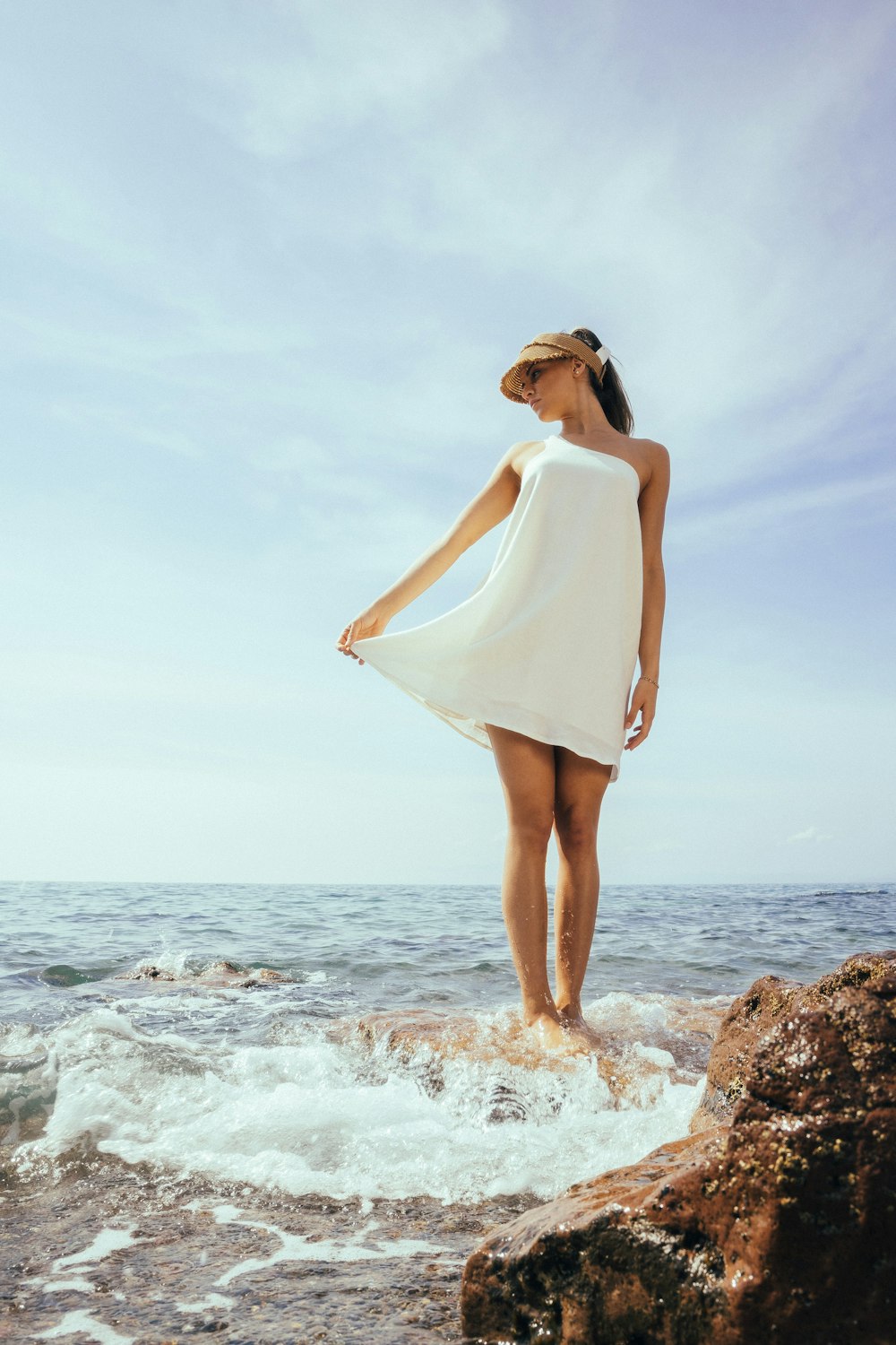 a woman standing on top of a rock near the ocean