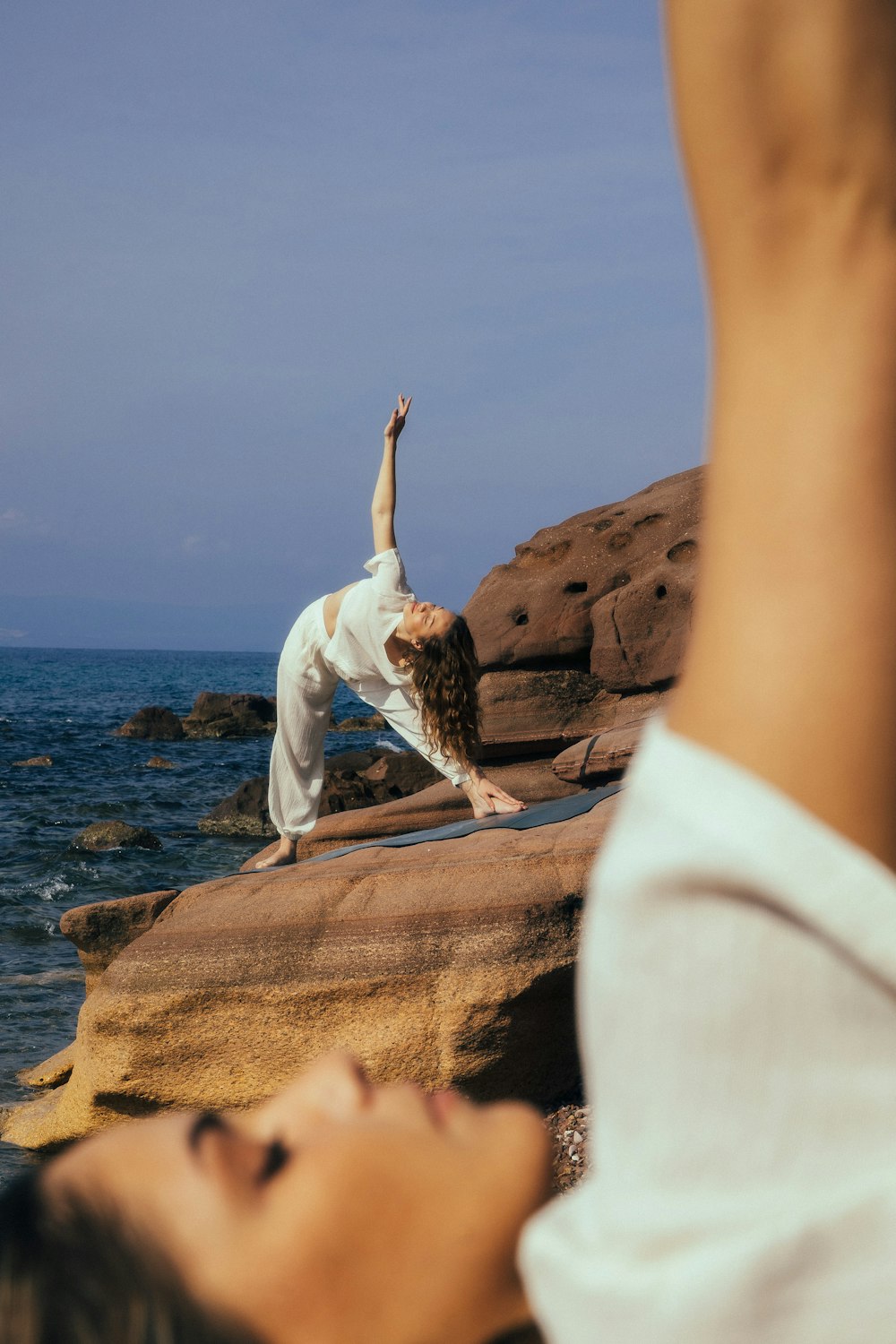 a woman doing a yoga pose on a rock near the ocean