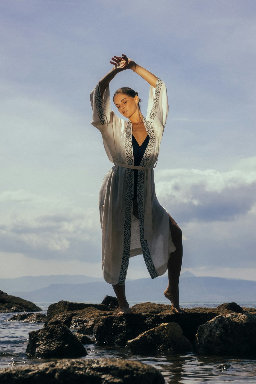 a woman standing on rocks doing a yoga pose
