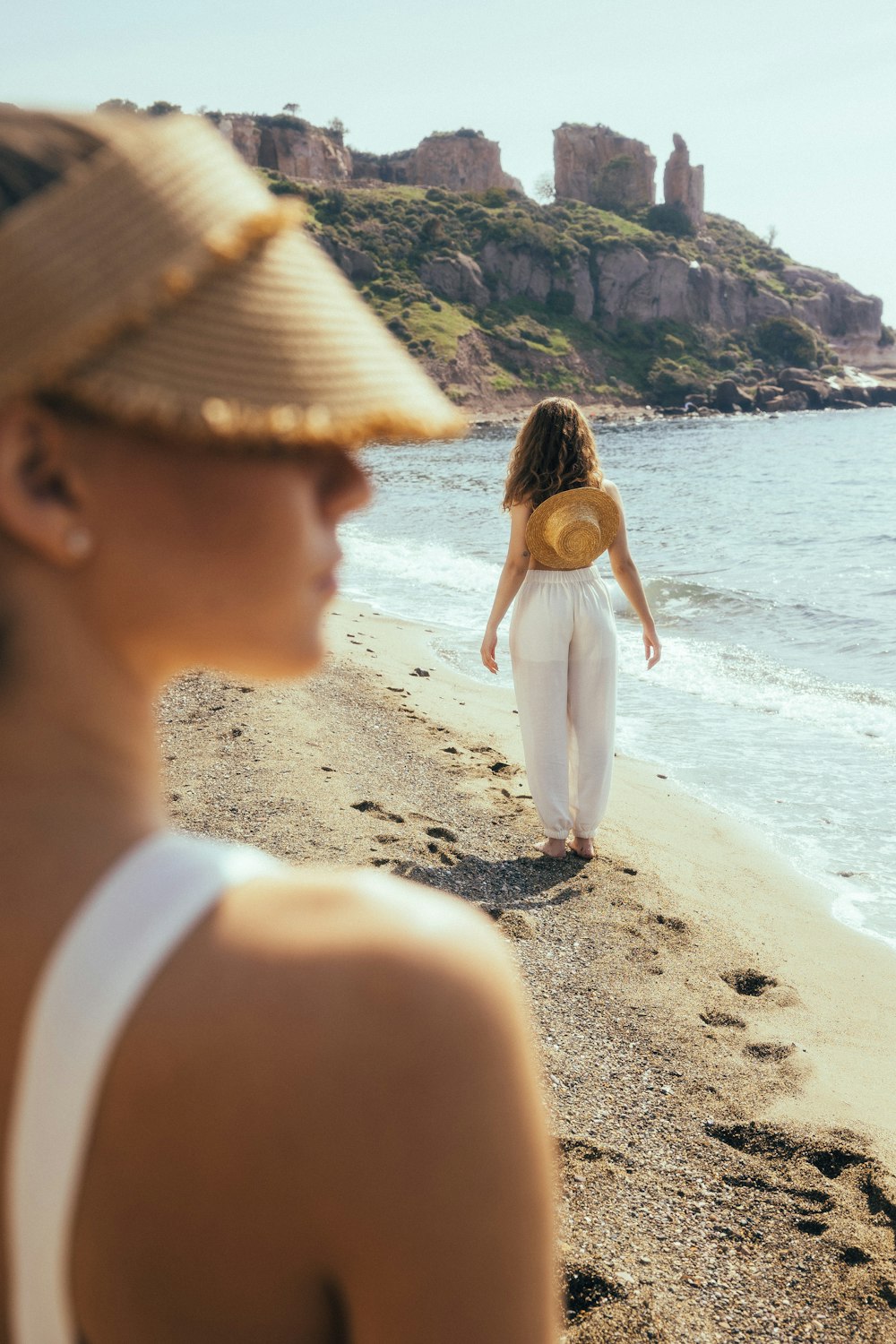 a woman standing on top of a beach next to the ocean