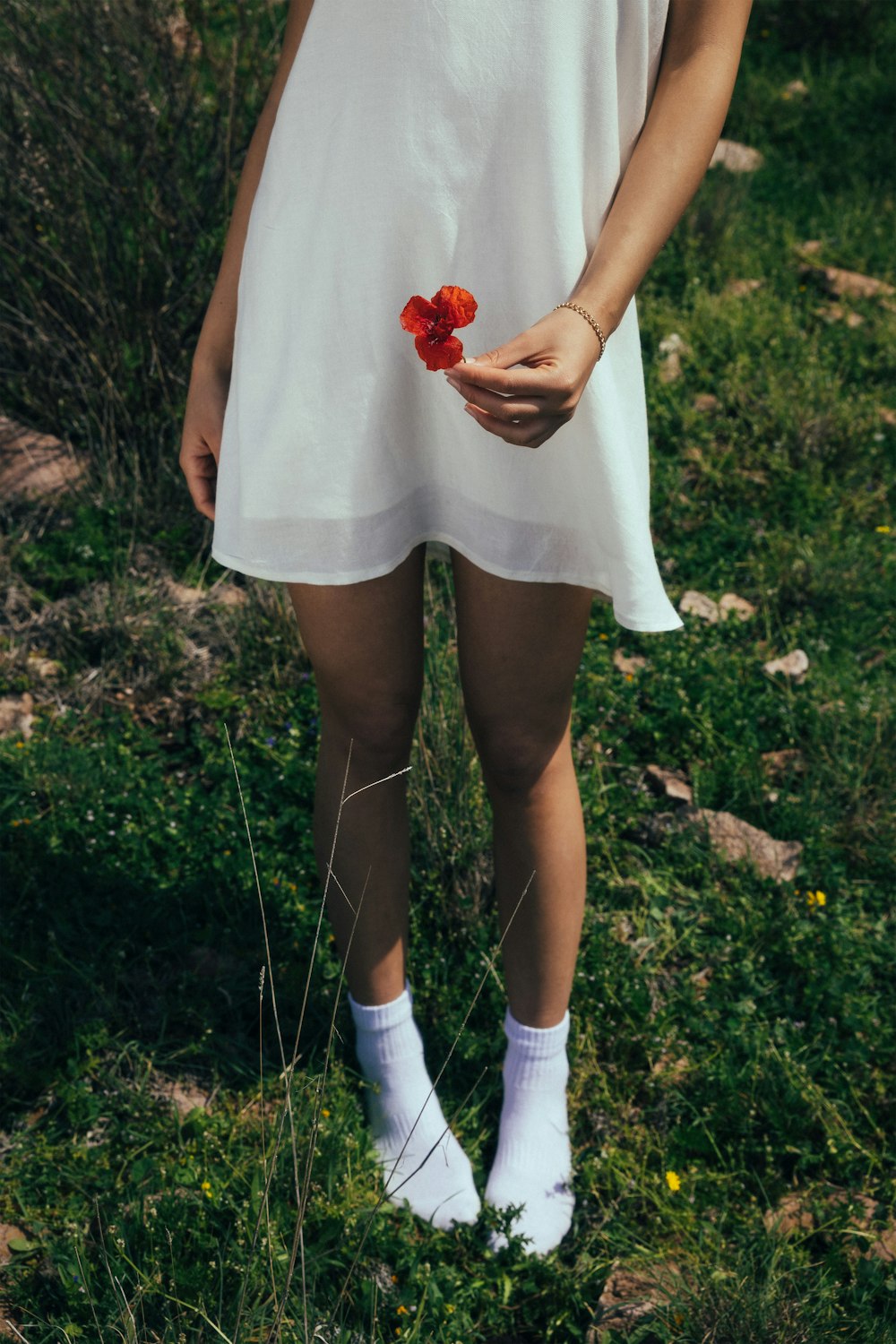 a woman in a white dress holding a flower