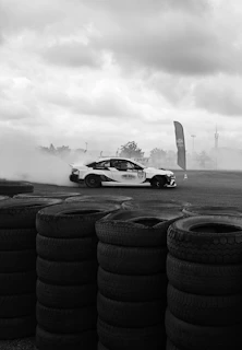 Dynamic photo of a JDM car drifting on a racetrack, smoke billowing from the tires.