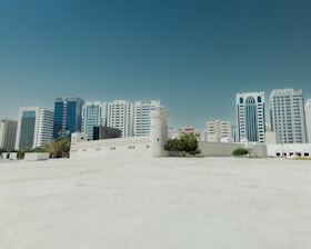 a large white building with a lot of tall buildings in the background