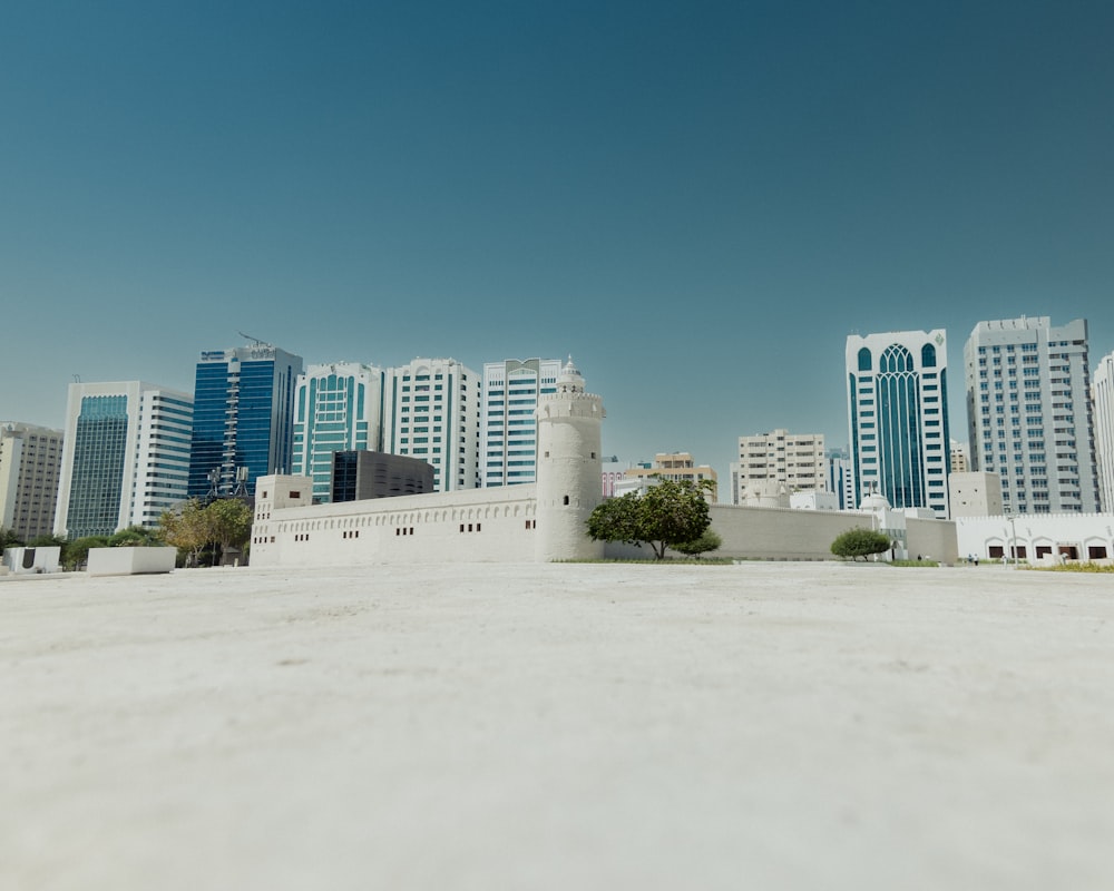 a large white building with a lot of tall buildings in the background