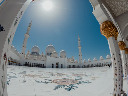 A peaceful mosque courtyard with intricate Islamic geometric patterns in the background, shining under soft sunlight.