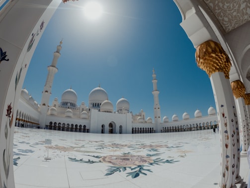 A peaceful mosque courtyard with green and blue accents under a clear sky.