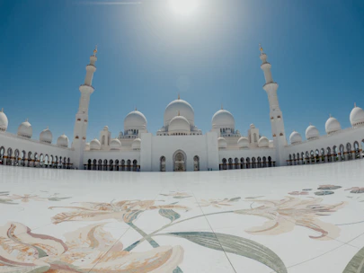 A serene mosque courtyard bathed in warm afternoon light, framed by intricate geometric patterns.
