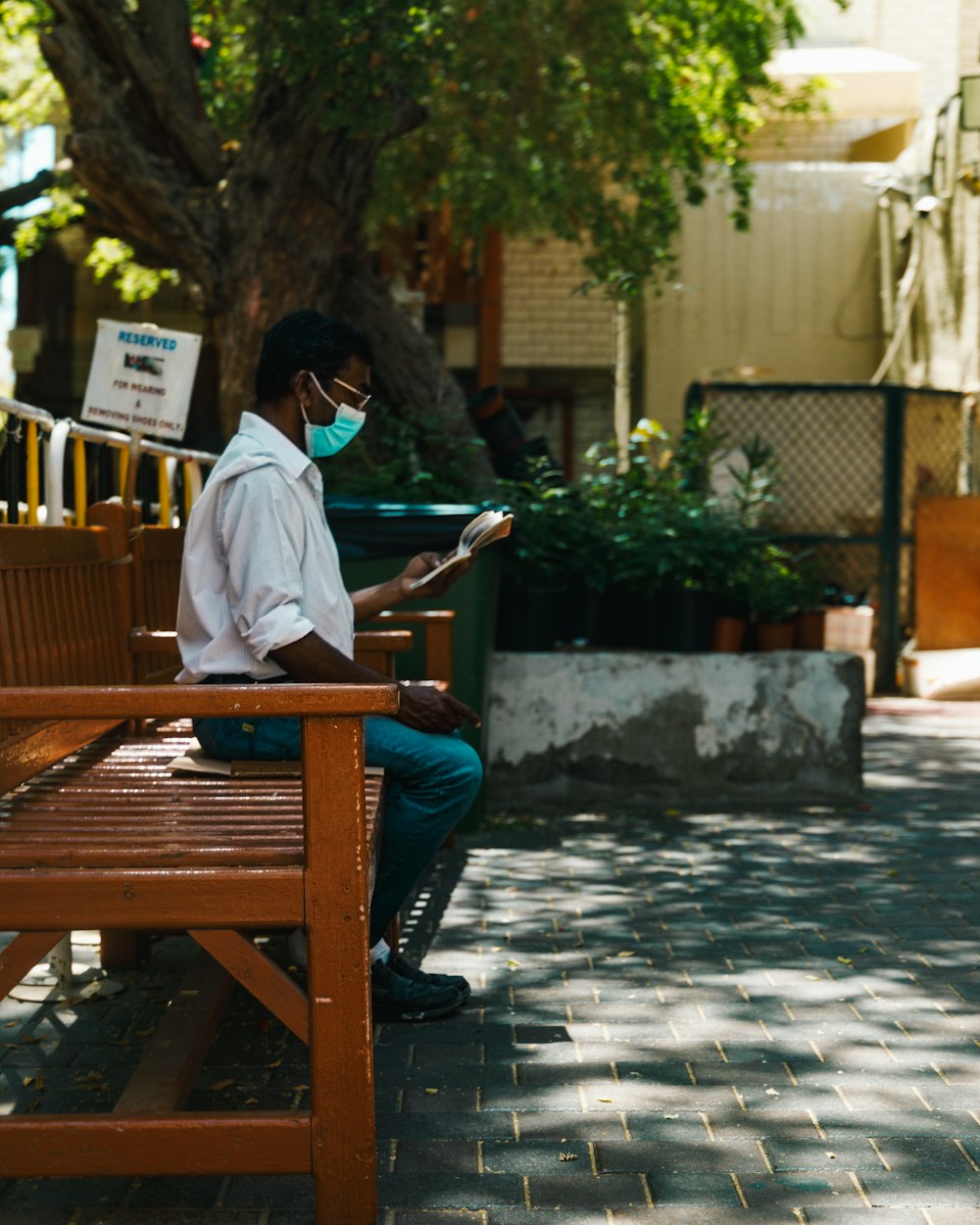 a man sitting on a wooden bench wearing a face mask